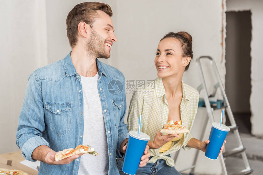在新公寓中一对幸福的年轻夫妇拿着纸杯图片