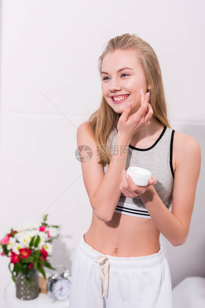 快乐的年轻女人涂面霜图片