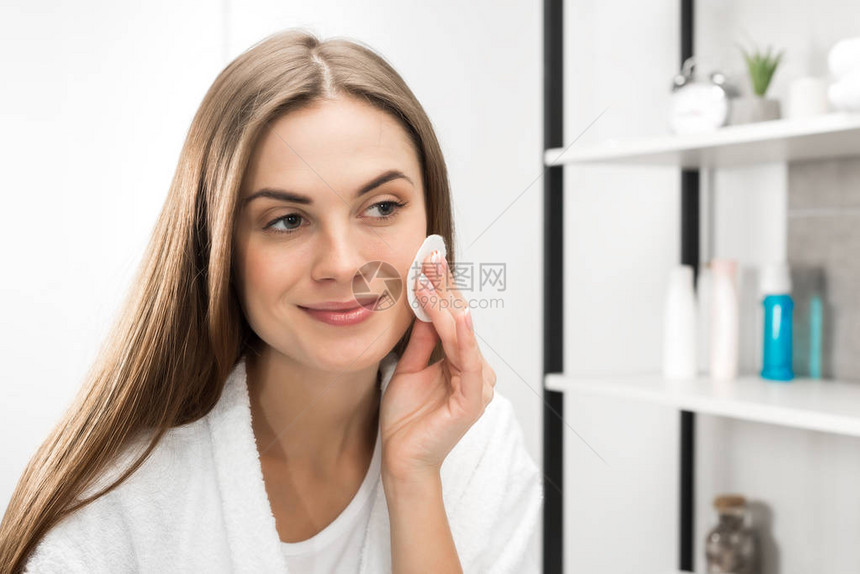 女人用化妆棉擦脸看着镜子图片