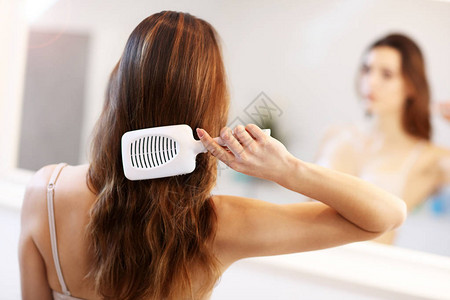 图片显示年轻女子在浴室里照顾头发背景图片