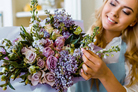 微笑的女花店在花店里用丁香和玫瑰布置花束图片