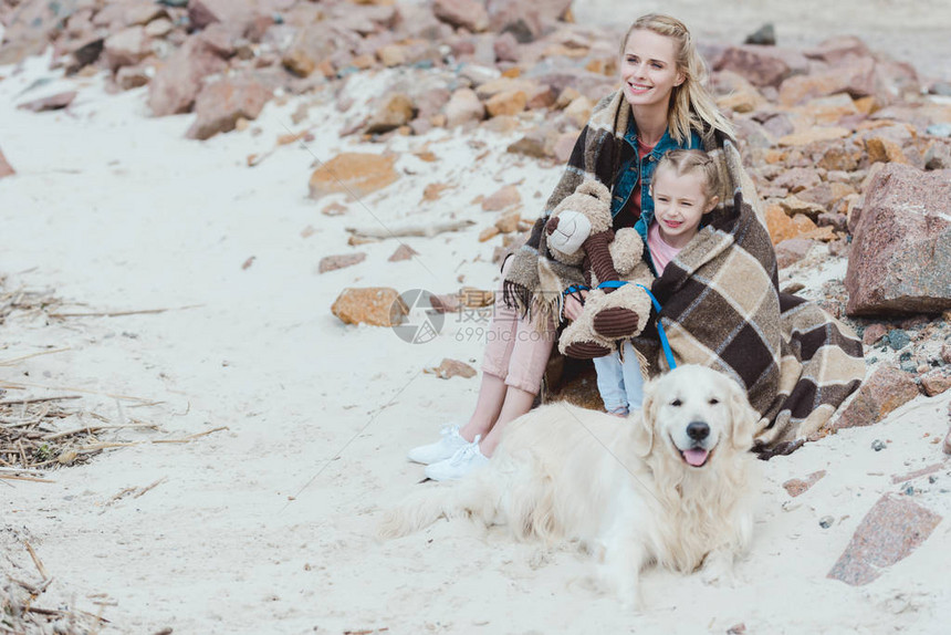 母亲和女儿被用毯子在岸上与黄金采图片