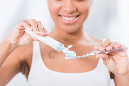 将牙膏涂在牙刷上的年轻妇女有图片