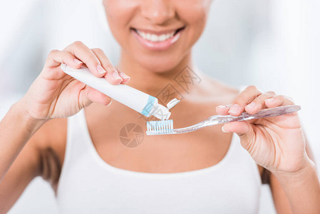 将牙膏涂在牙刷上的年轻女图片