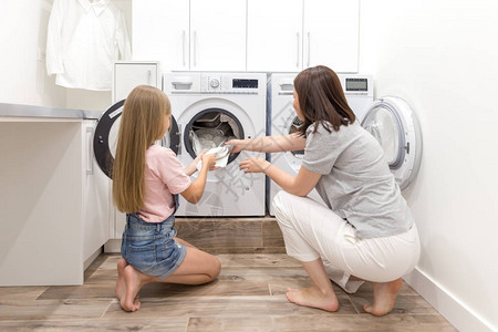 洗衣机和烘干机附近的洗衣间洗衣房内母亲和女儿背景图片