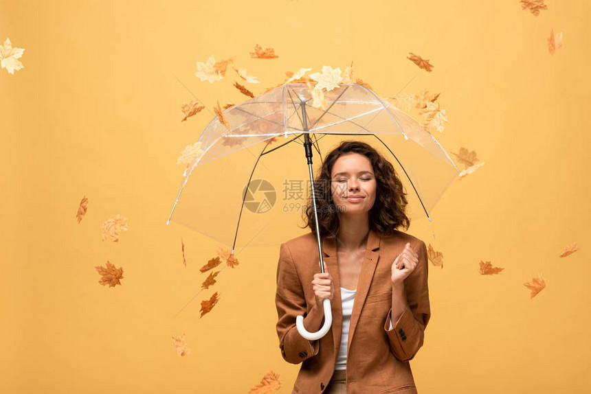 穿着棕色夹克的快乐卷发女人闭着眼睛拿着雨伞在坠落图片