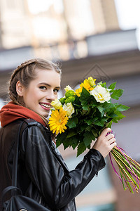 街上拿着一束鲜花的幸福女人的侧面图图片