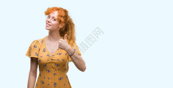 年轻红发女红发女士用手做快乐的拇指举起手势赞同观看摄影机并展图片
