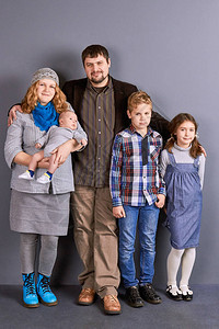 灰色背景的白种人家庭微笑的欧洲家庭与男孩女孩和婴儿隔离在灰色的背景幸图片