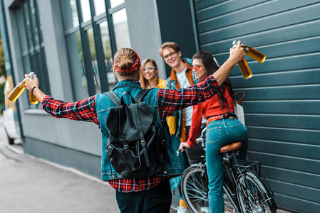 兴奋的男潮人带啤酒给街上快乐的朋友们图片