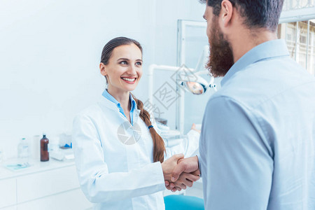 一位可靠而快乐的女牙医或牙科医生在现代诊所的牙科办公室与病图片