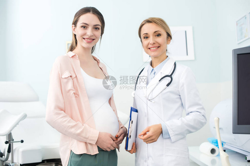 年轻孕妇在诊所与微笑的妇科图片