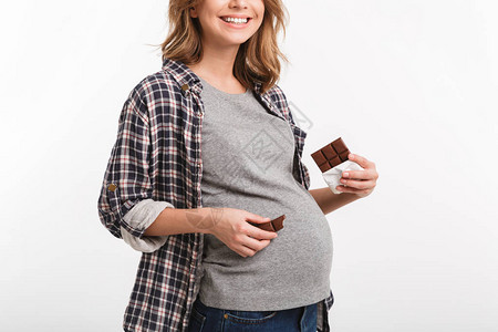 带着巧克力的孕妇在肚子附近露着微笑的容拍摄图片