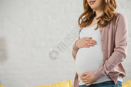 笑着微笑的孕妇在家中摸肚子图片