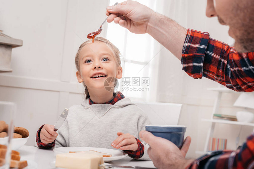 父亲用果酱和可爱的笑女孩拿图片