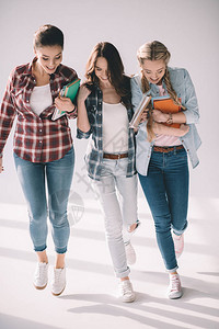 三个快乐的漂亮女学生带着白色的书背景图片
