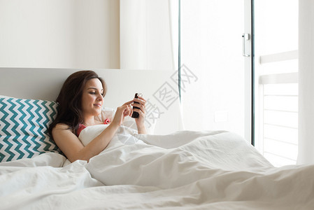 床边用智能手机检查社交应图片