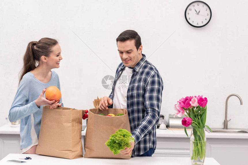 从杂货店纸袋中提取蔬菜和水果的美貌成人图片