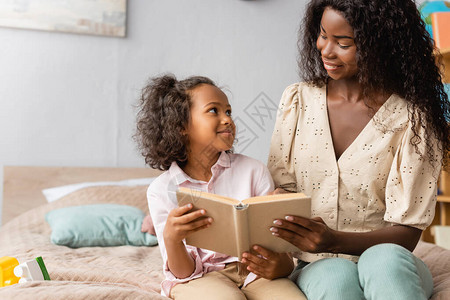 非洲母亲和孩子在看书的时候互相看着对方图片