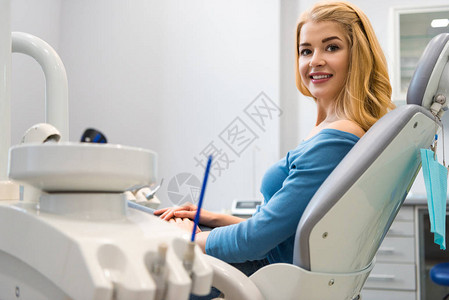 坐在牙医办公室牙科椅上的笑着微图片