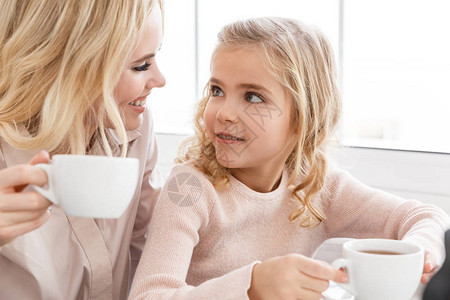 妈和女儿在咖啡馆喝茶时互相看图片