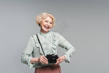 快乐的年长妇女用古董胶片摄像头在图片