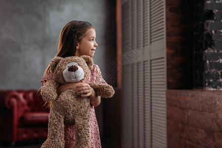 漂亮的小孩在家抱着泰迪熊图片