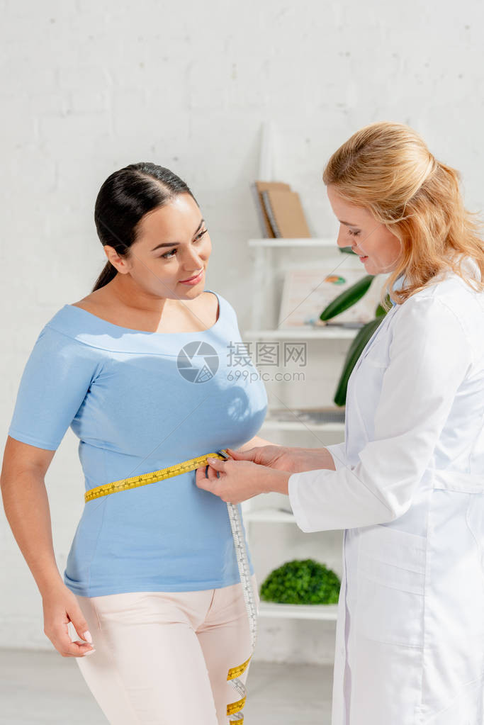具有吸引力的营养学家测量病人在诊所内用计量图片