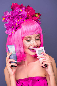 笑着的年轻女子带着粉红色的波布剪花和鲜花在头发中图片