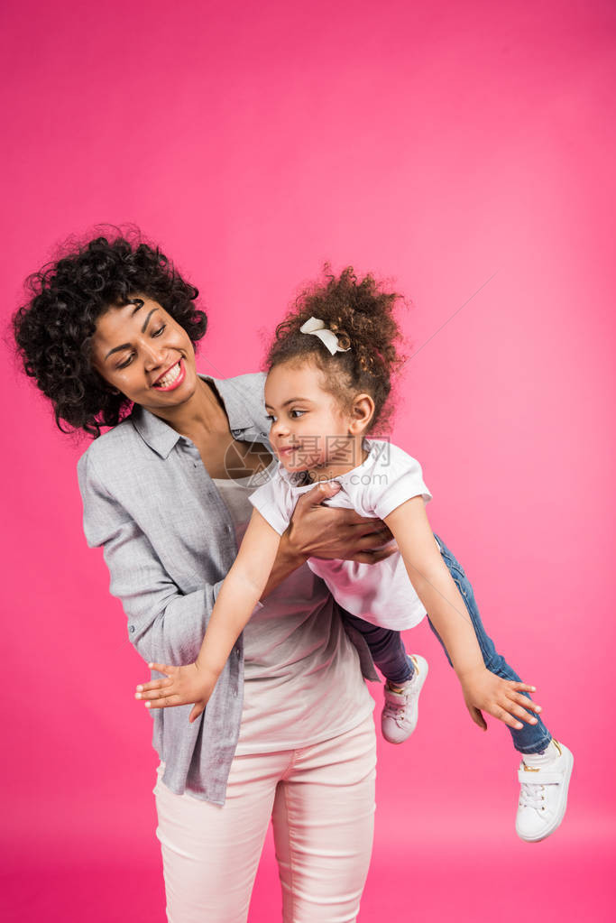 微笑的母亲与女儿玩耍将她握在被粉红图片