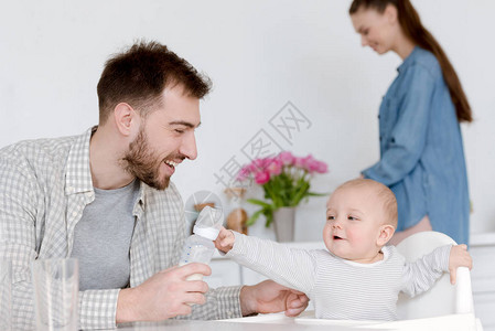 微笑的父亲用奶瓶喂婴儿奶母亲图片