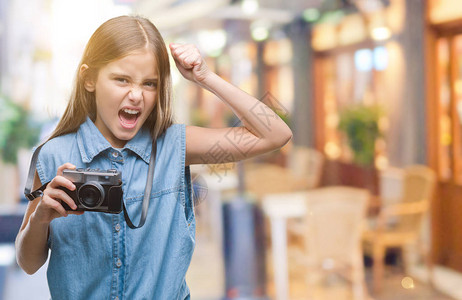 年轻漂亮的女孩在孤立的背景下用老式相机拍照图片