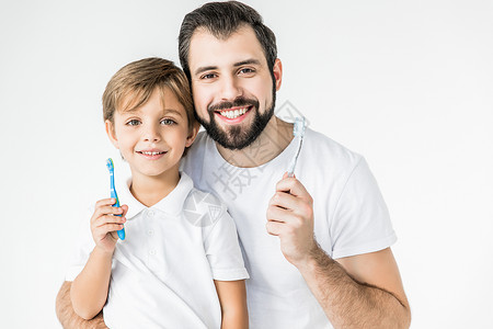 快乐的父亲和儿子拿着牙刷笑着在背景图片