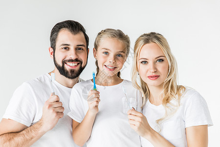 幸福的年轻家庭拿着牙刷微笑着与白色图片