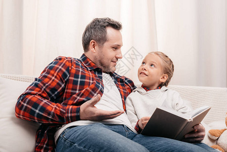 快乐的父亲和女儿在阅读书本时图片