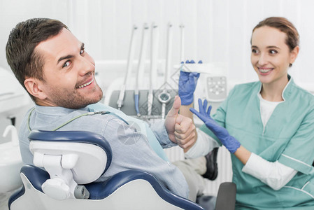 欢快的病人在拿着牙膏的女牙医附近竖起大拇指图片