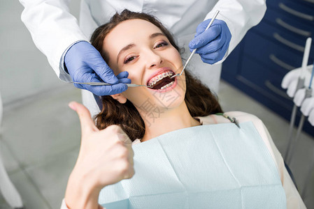 戴着乳胶手套的牙医检查戴牙套张开大拇指的漂图片