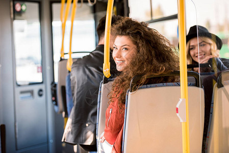 坐在城市公共汽车上坐在一起的美丽笑着微图片