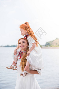 带着可爱的红发女儿在海边脖子上抱图片