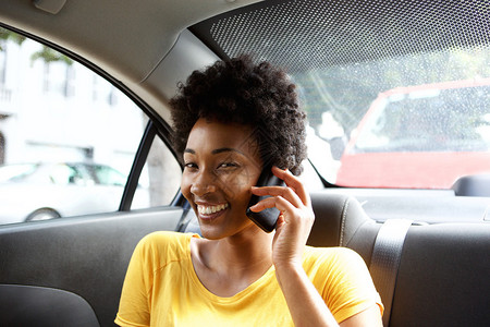 坐在汽车后座的非洲年轻女士在手机上聊天的近亲肖像图片