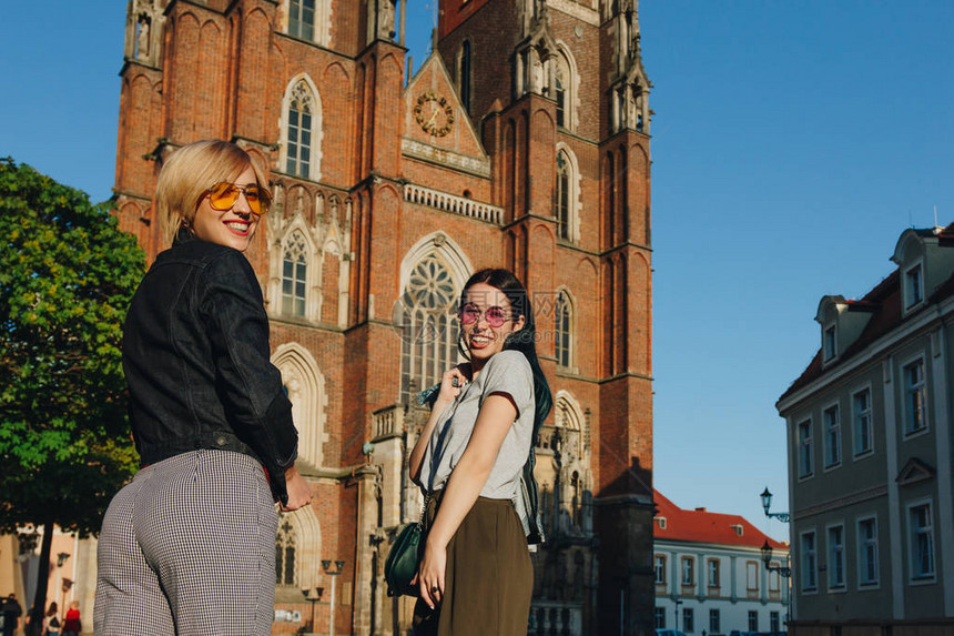 两个有魅力的笑着女人站在wroclaw大教堂前图片