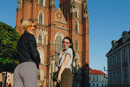 两个有魅力的笑着女人站在wroclaw大教堂前背景图片