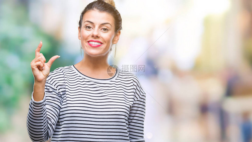 年轻漂亮的女人休闲条纹毛衣在孤立的背景上微笑和自信地用手指做大小标志图片