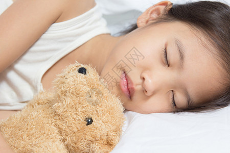 带着熊睡觉的亚洲孩子图片