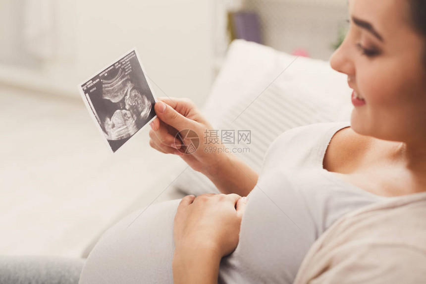 快乐的期待女士享受她未出生孩子的第一张照片图片