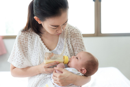 喂养婴儿亚洲母亲用奶瓶给刚出图片