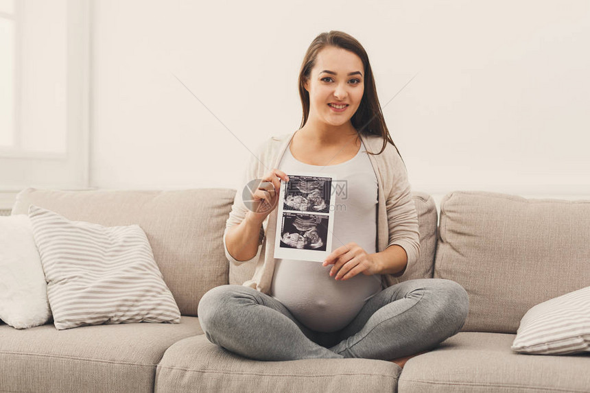 快乐的期待女士享受她未出生孩子的第一张照片图片