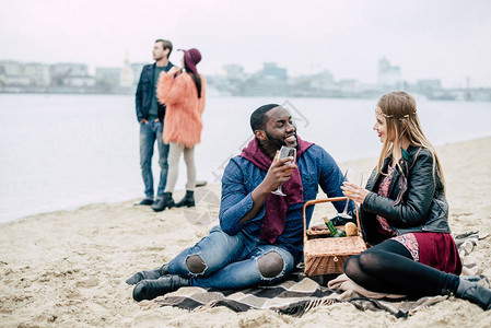 美丽的年轻浪漫情侣坐在沙滩上图片
