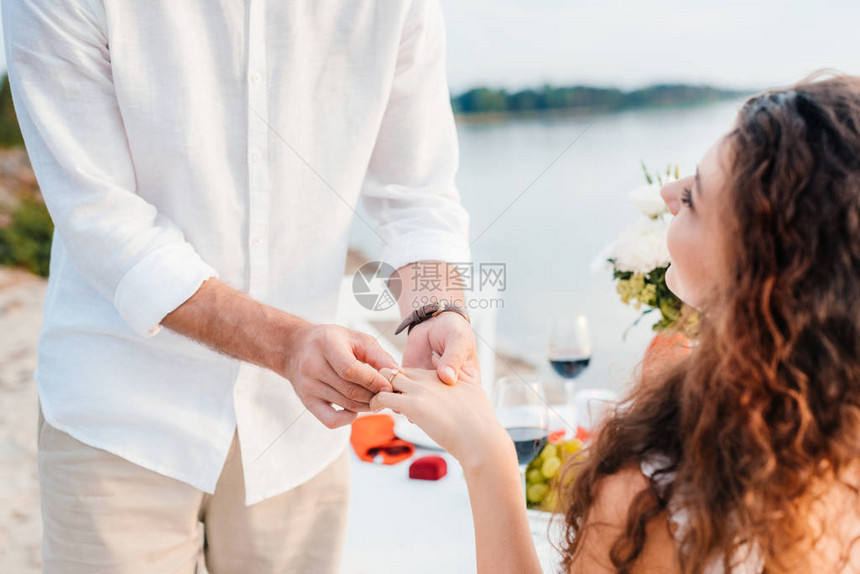 在浪漫约会求婚后男人在女人手指上戴戒指的图片