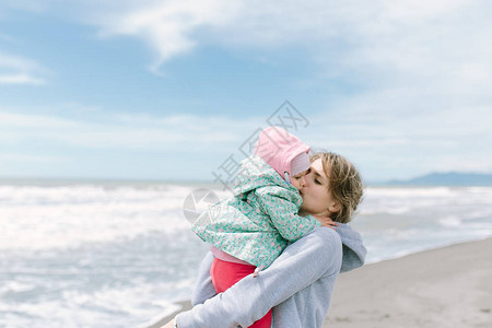 可爱的女婴和年轻母亲在海滨相图片
